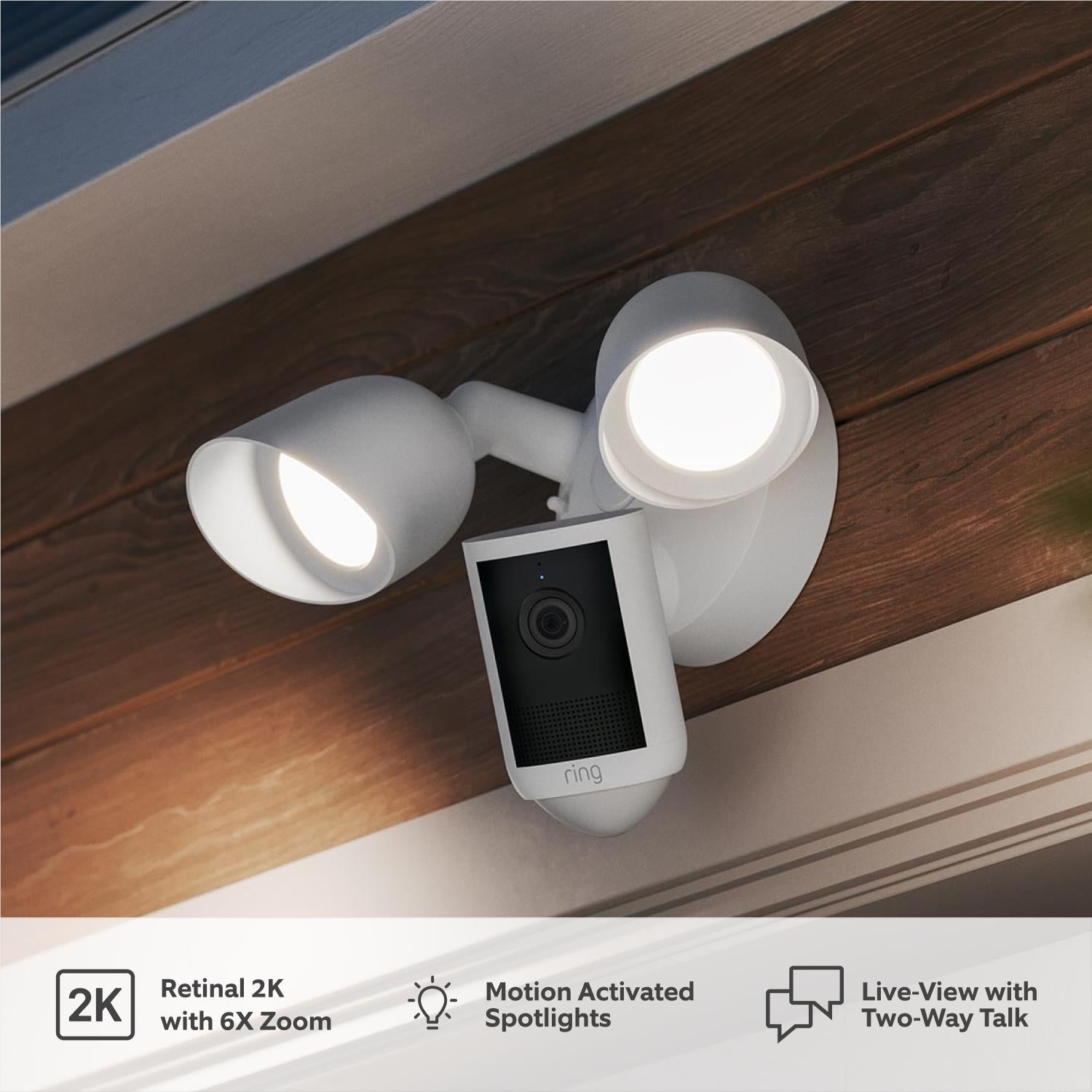White wired outdoor floodlight camera with dual spotlights mounted under a roof edge