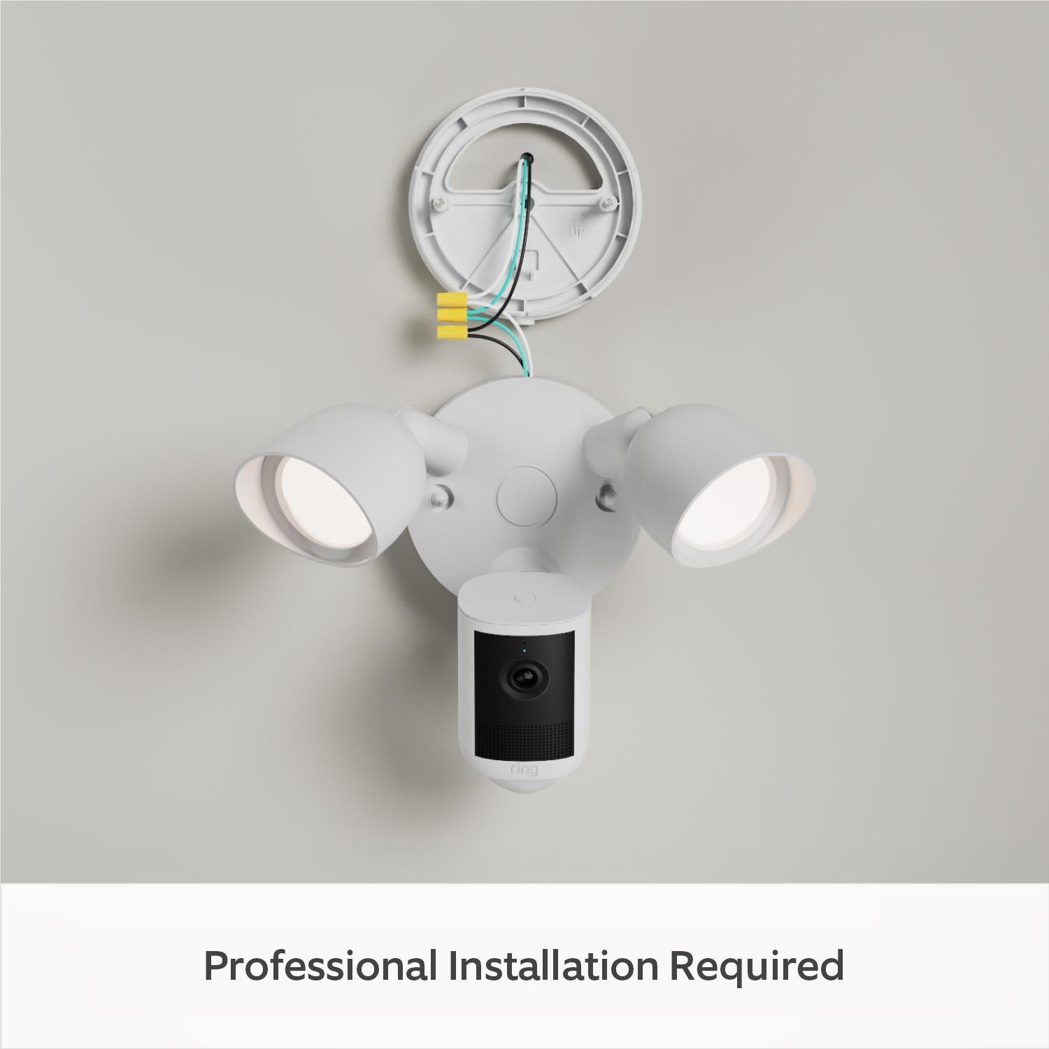White outdoor floodlight camera with exposed wiring and dual spotlight heads on mounting plate
