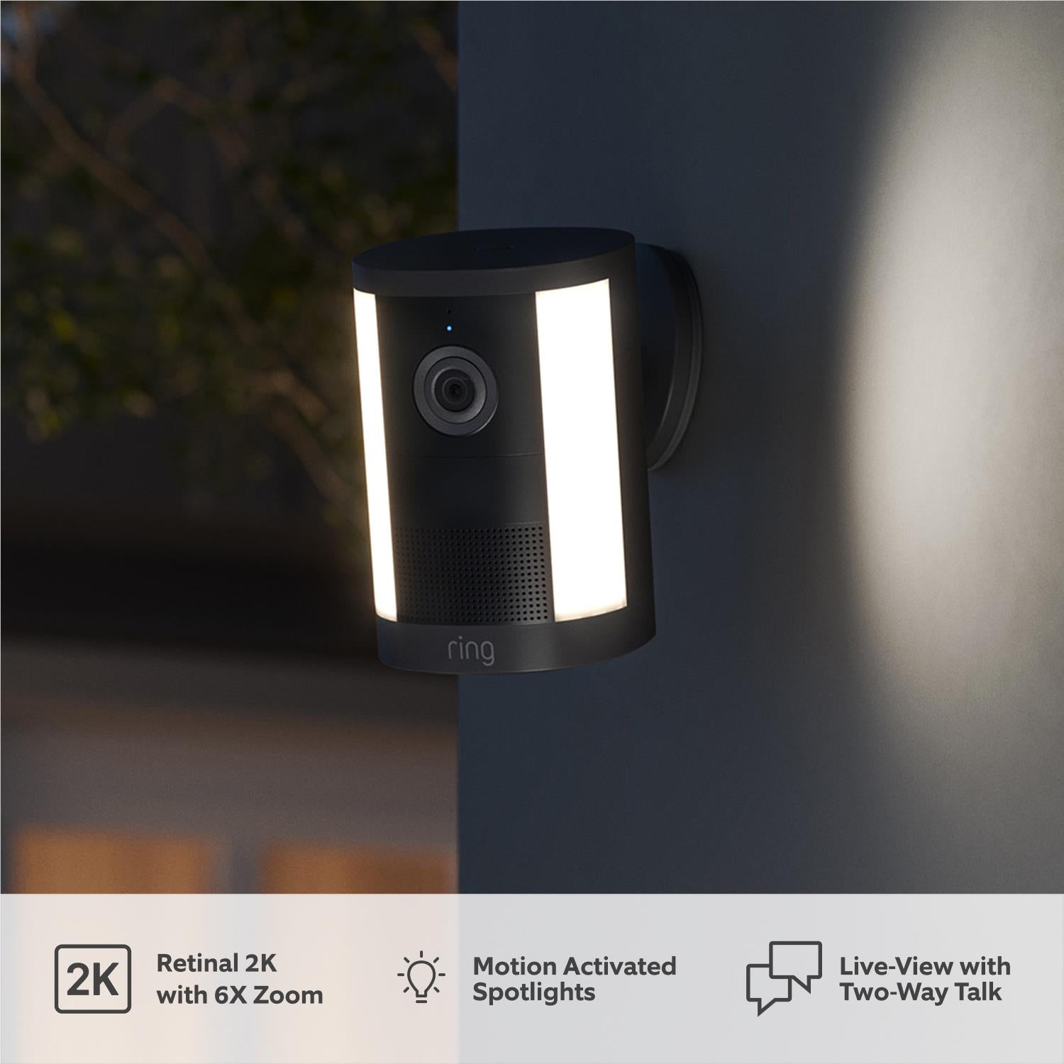 Black spotlight camera on wall with illuminated vertical light panel and lens