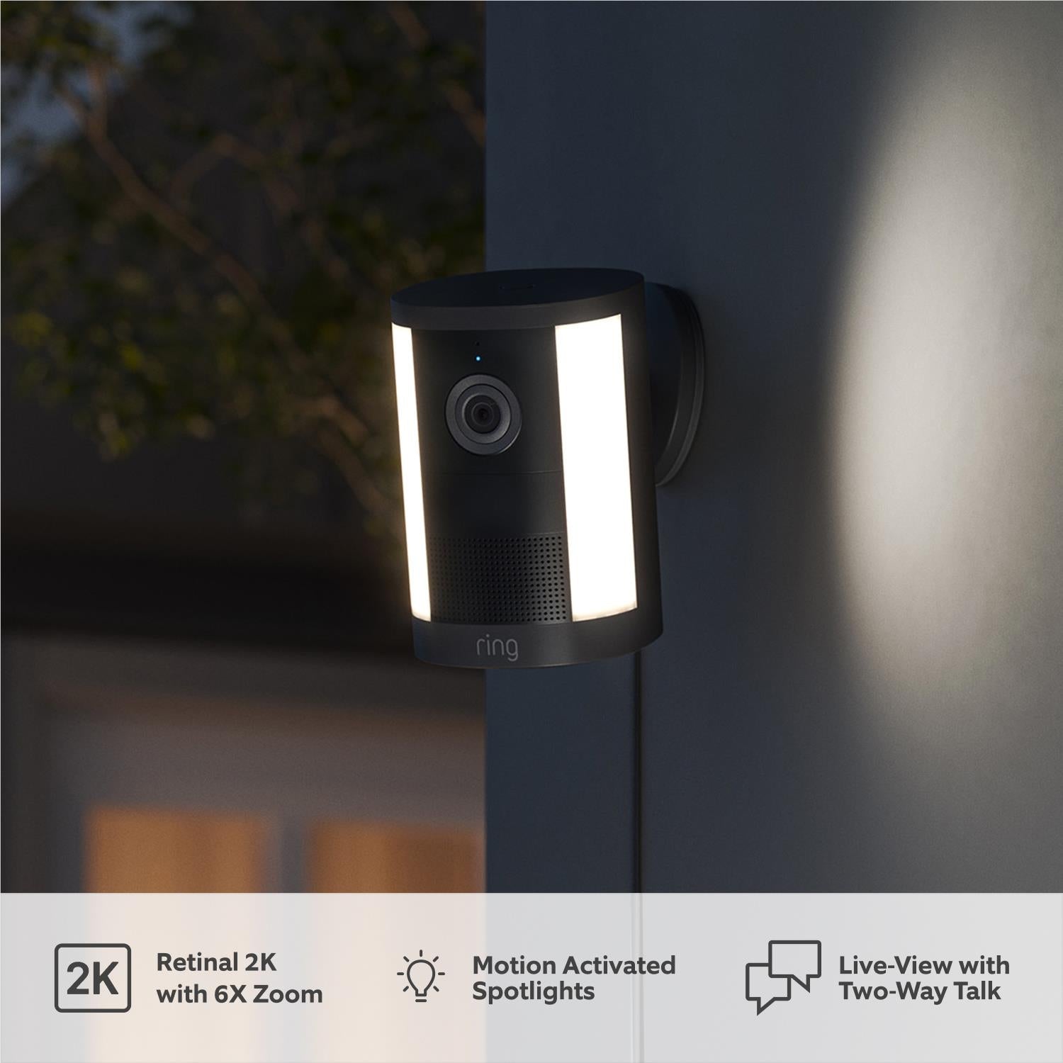 Black ring spotlight camera with bright vertical light panels and front lens on wall