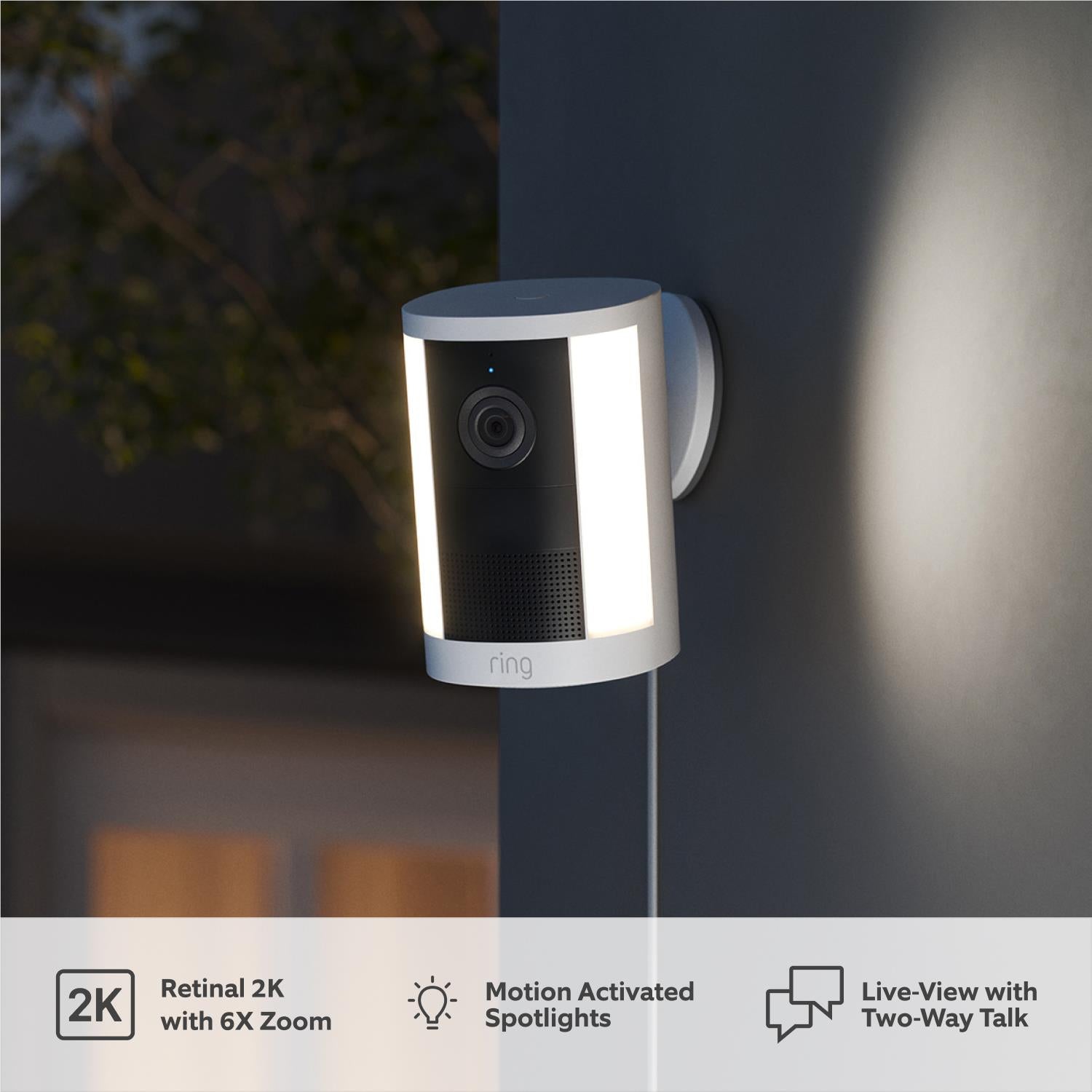 White spotlight security camera mounted on wall with built-in front light
