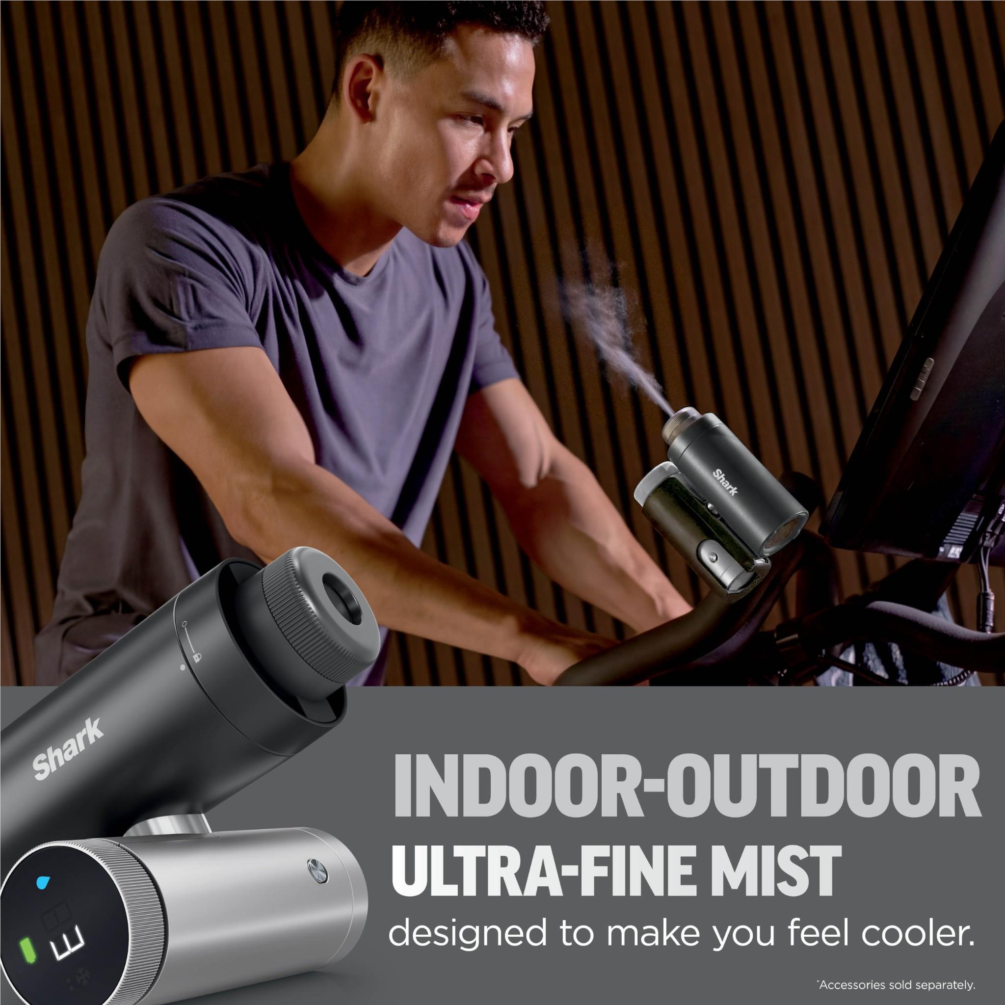 Charcoal handheld cooling fan in use, held near an indoor workspace