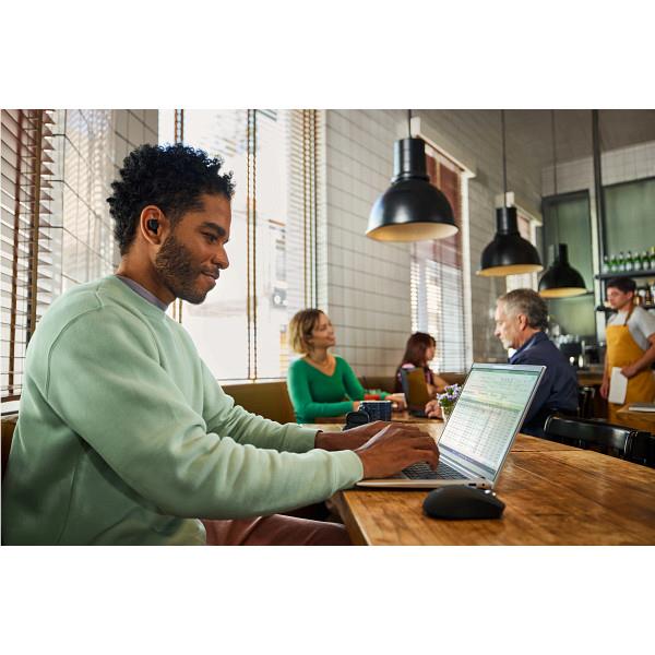 Person using a black wireless mouse while working at a desk