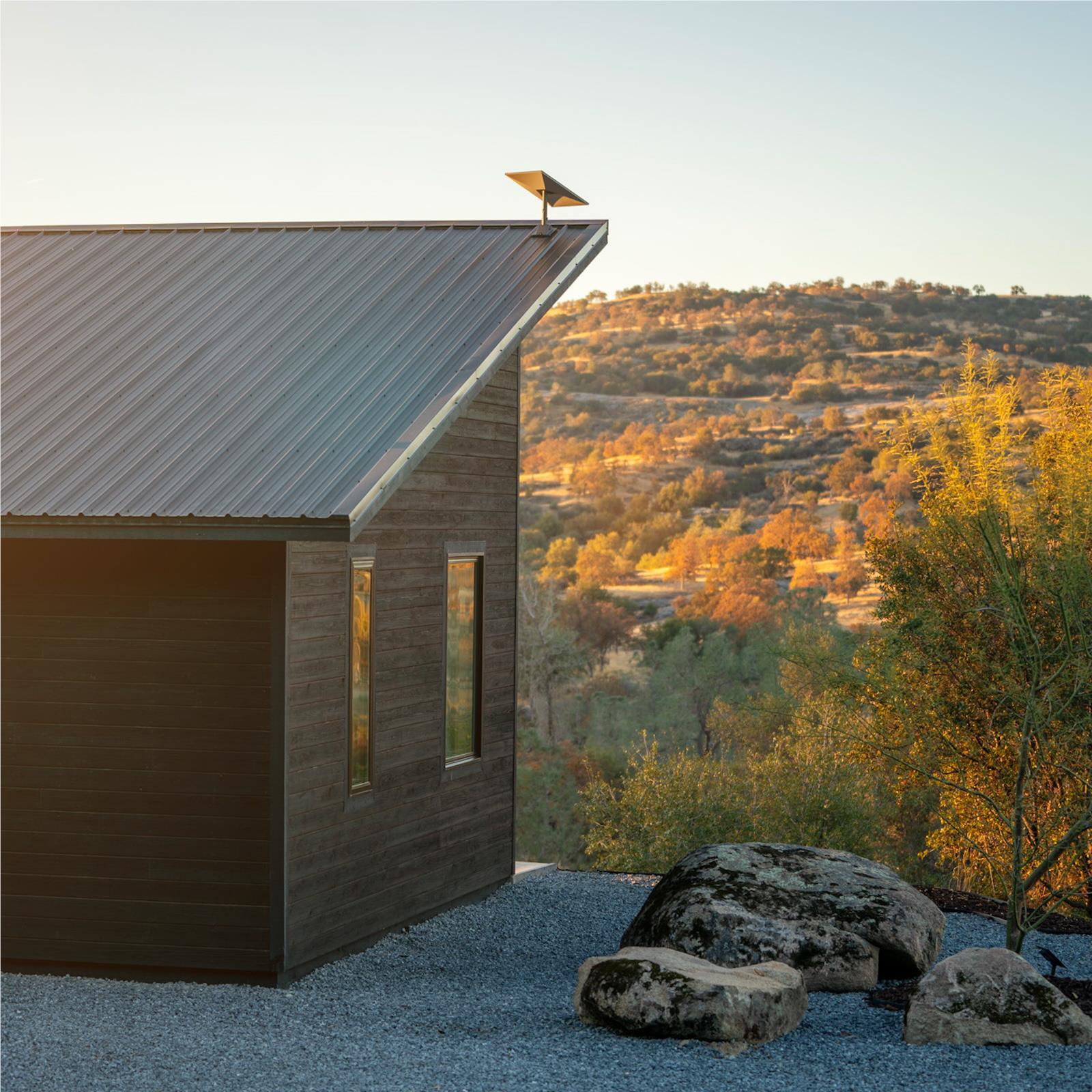Satellite internet dish on roof of house near rocks and surrounding trees