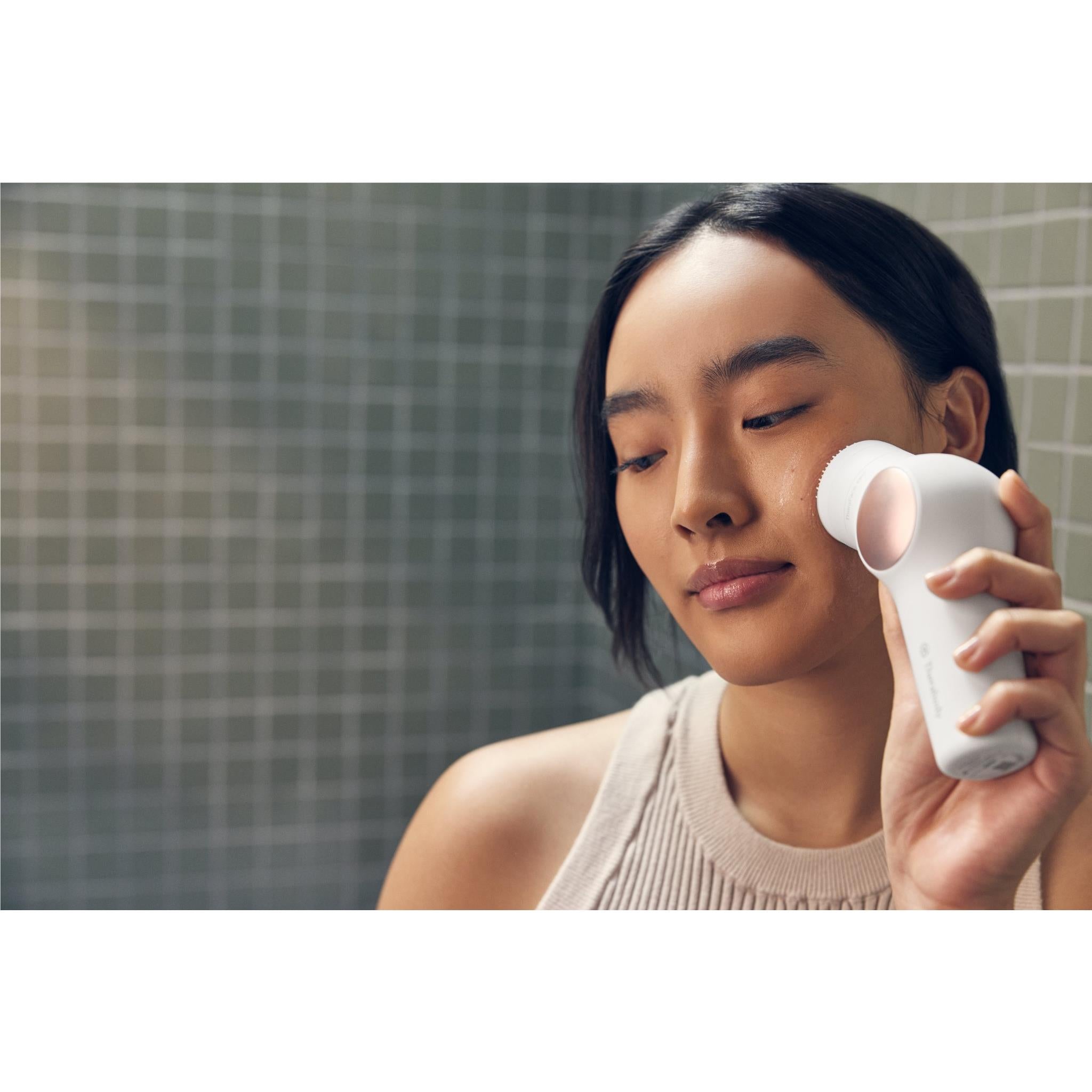 Person using white facial therapy device on cheek