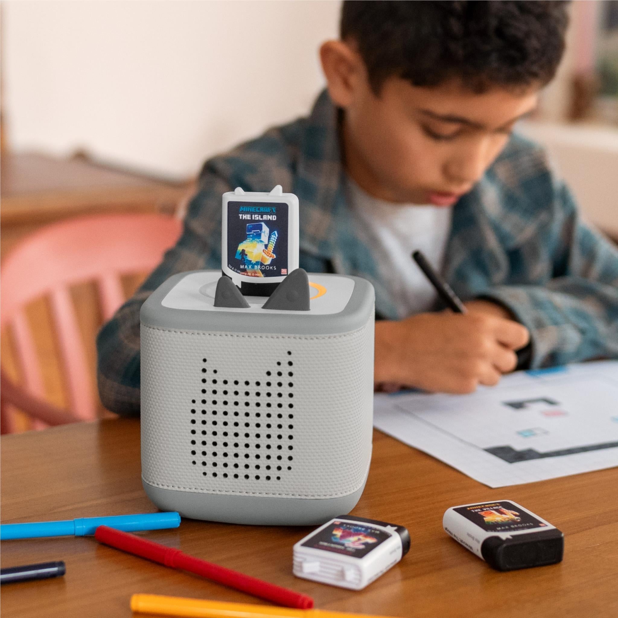 Audio Tonie in Toniebox while child writes at table