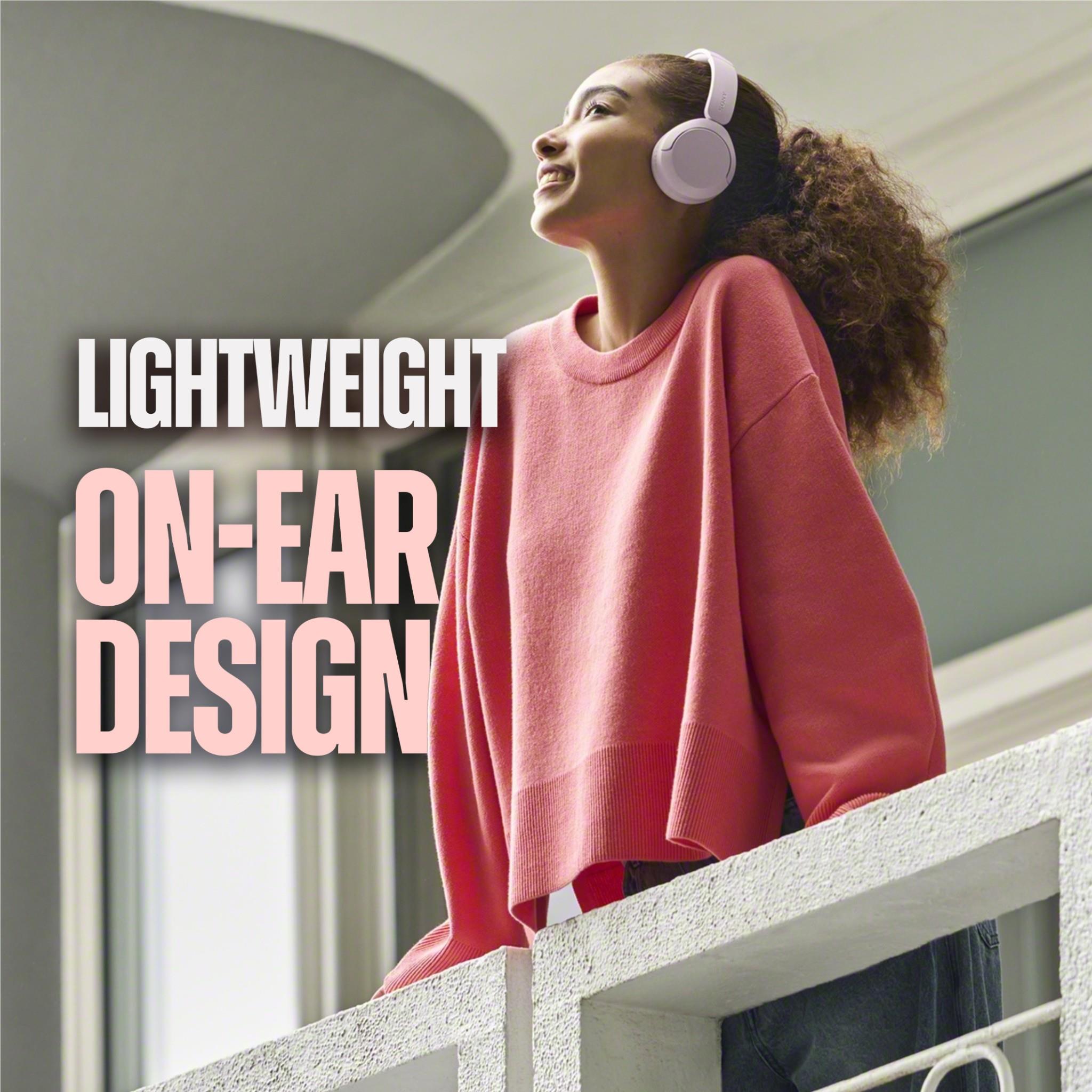 Coral red on-ear wireless headset worn on person, side profile with ear cups