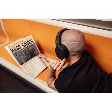 Person wearing black over-ear Bluetooth headphones while reaching toward a box