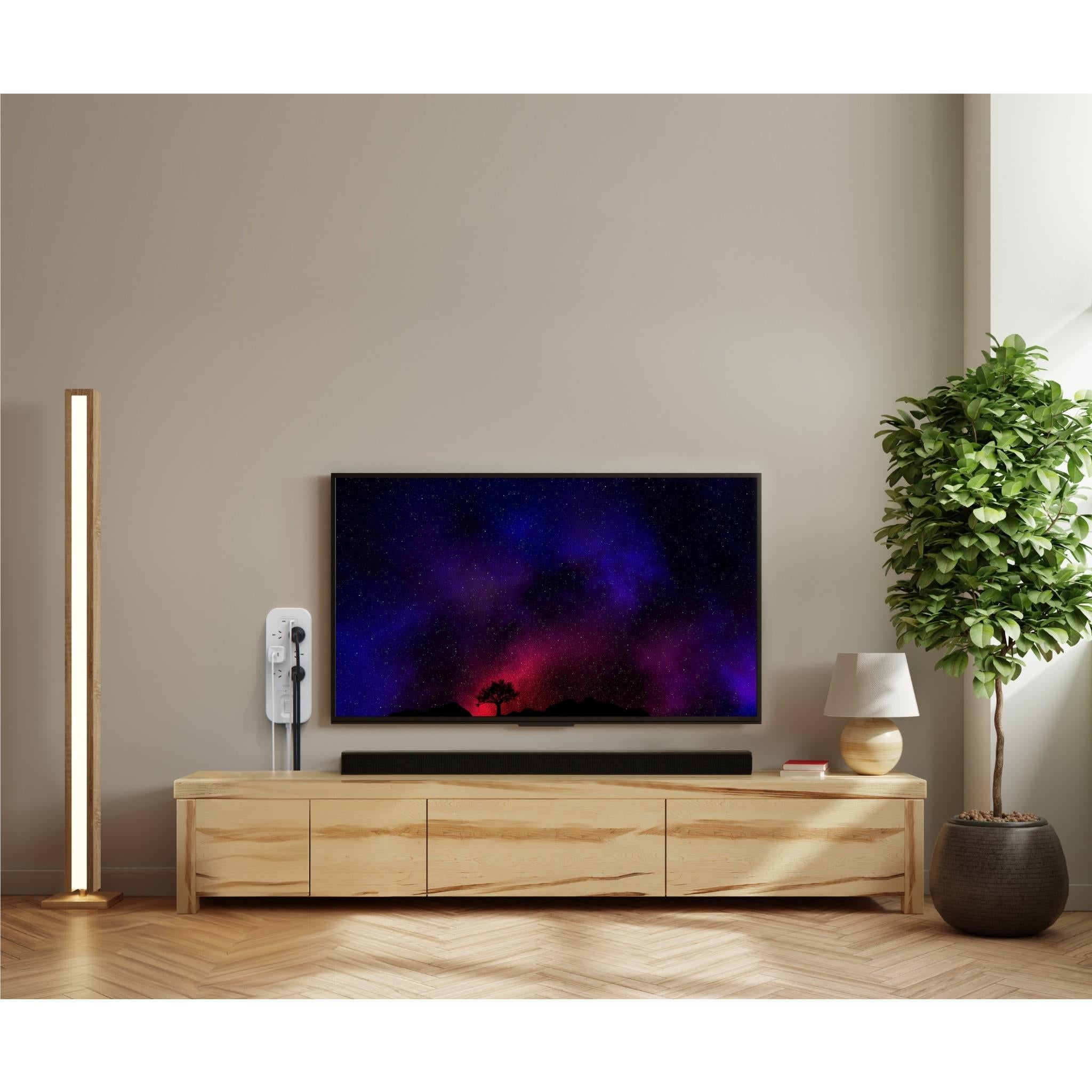 White 6-outlet surge protector with USB-C ports beside a TV stand