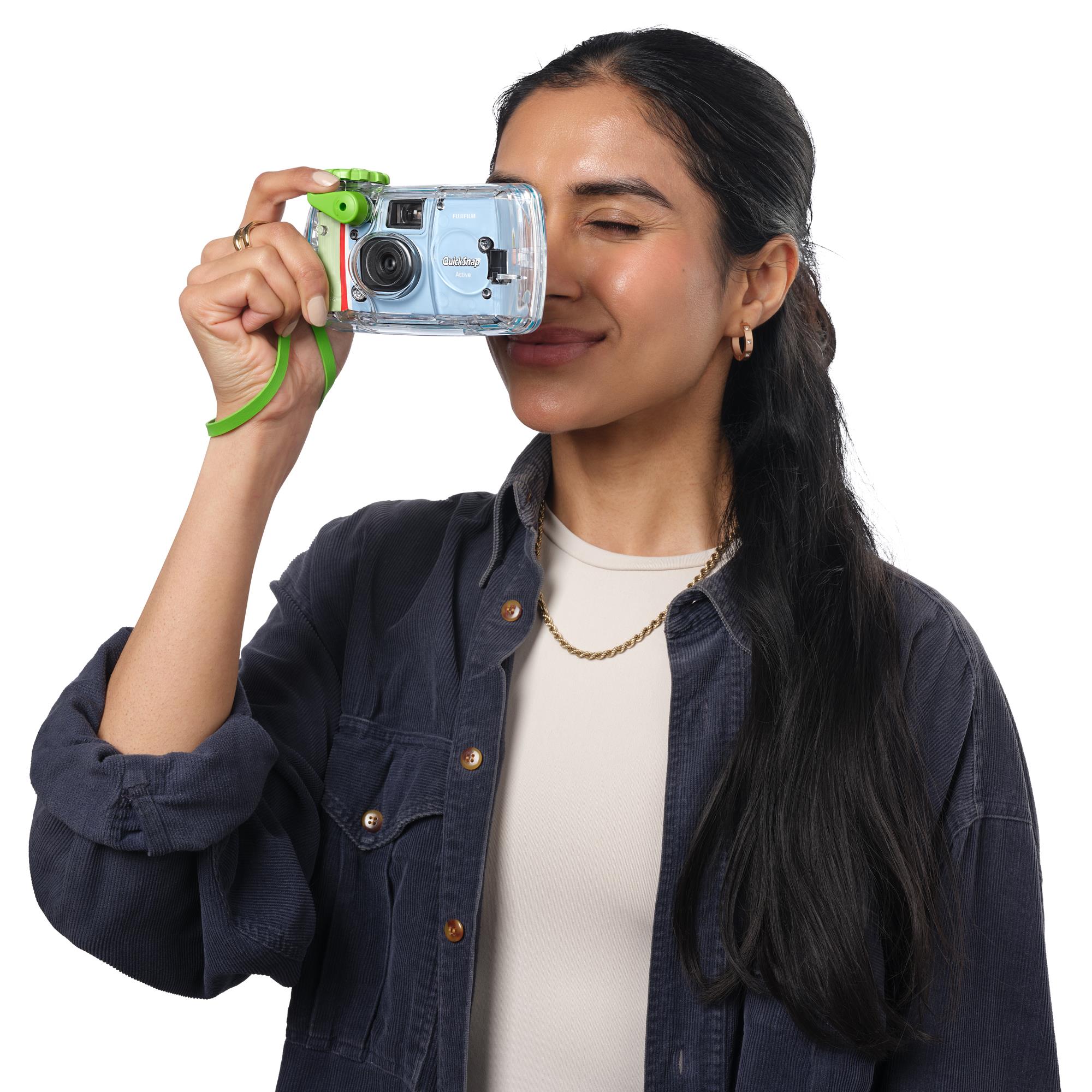 Fujifilm QuickSnap waterproof disposable camera held near face, light blue body, green strap