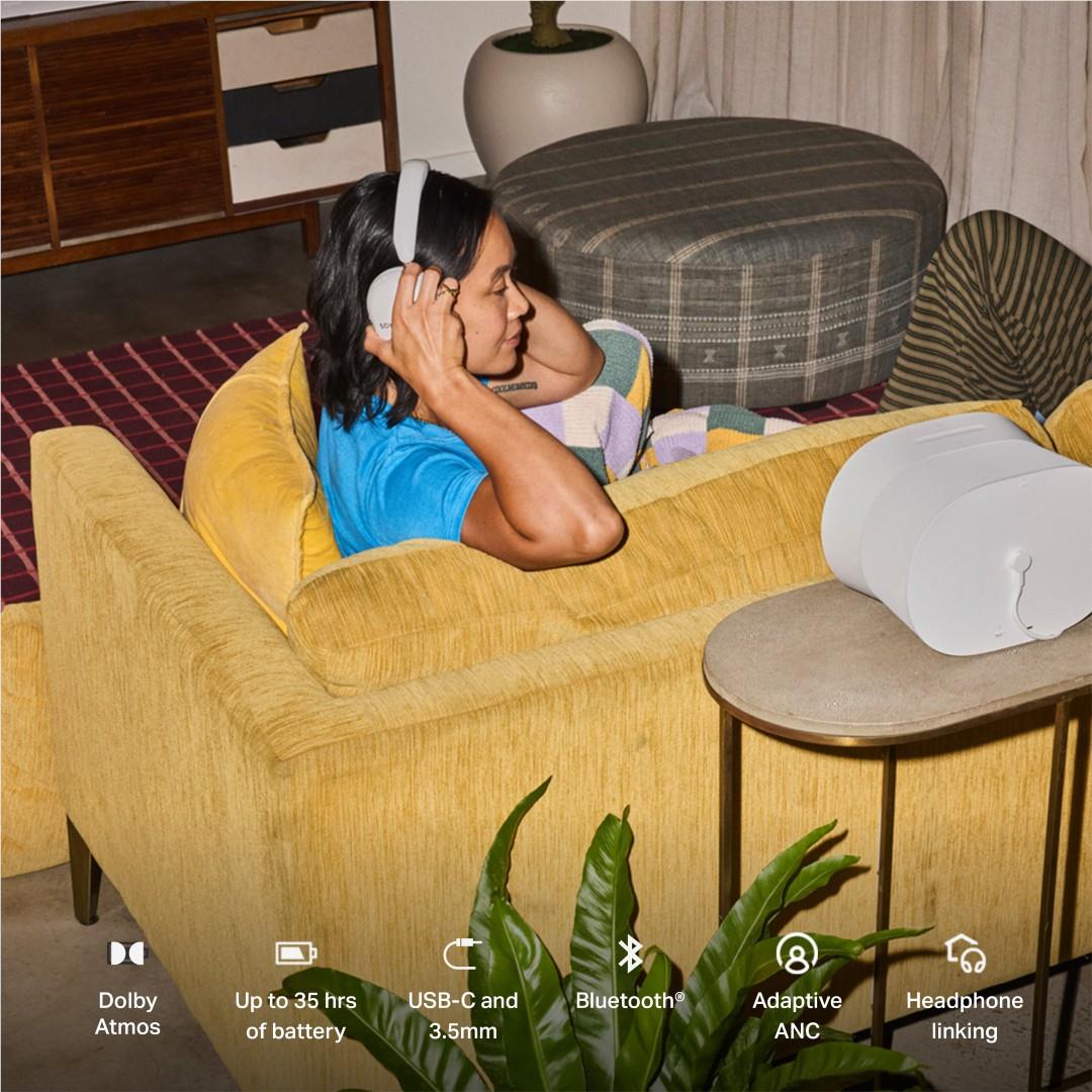 White over-ear noise cancelling headphones worn by a person reclining on a couch