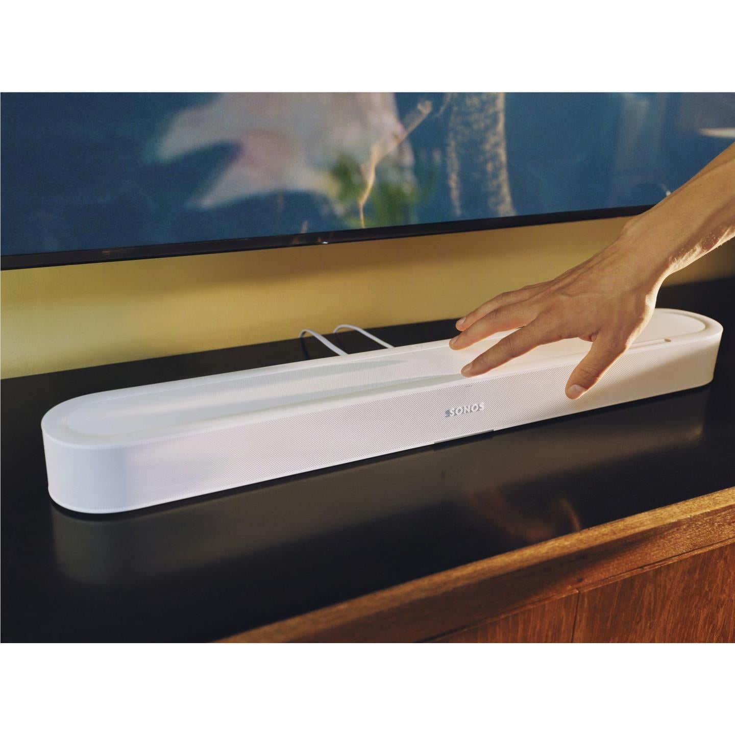 White Sonos Beam Ultra soundbar on console with hand reaching the controls