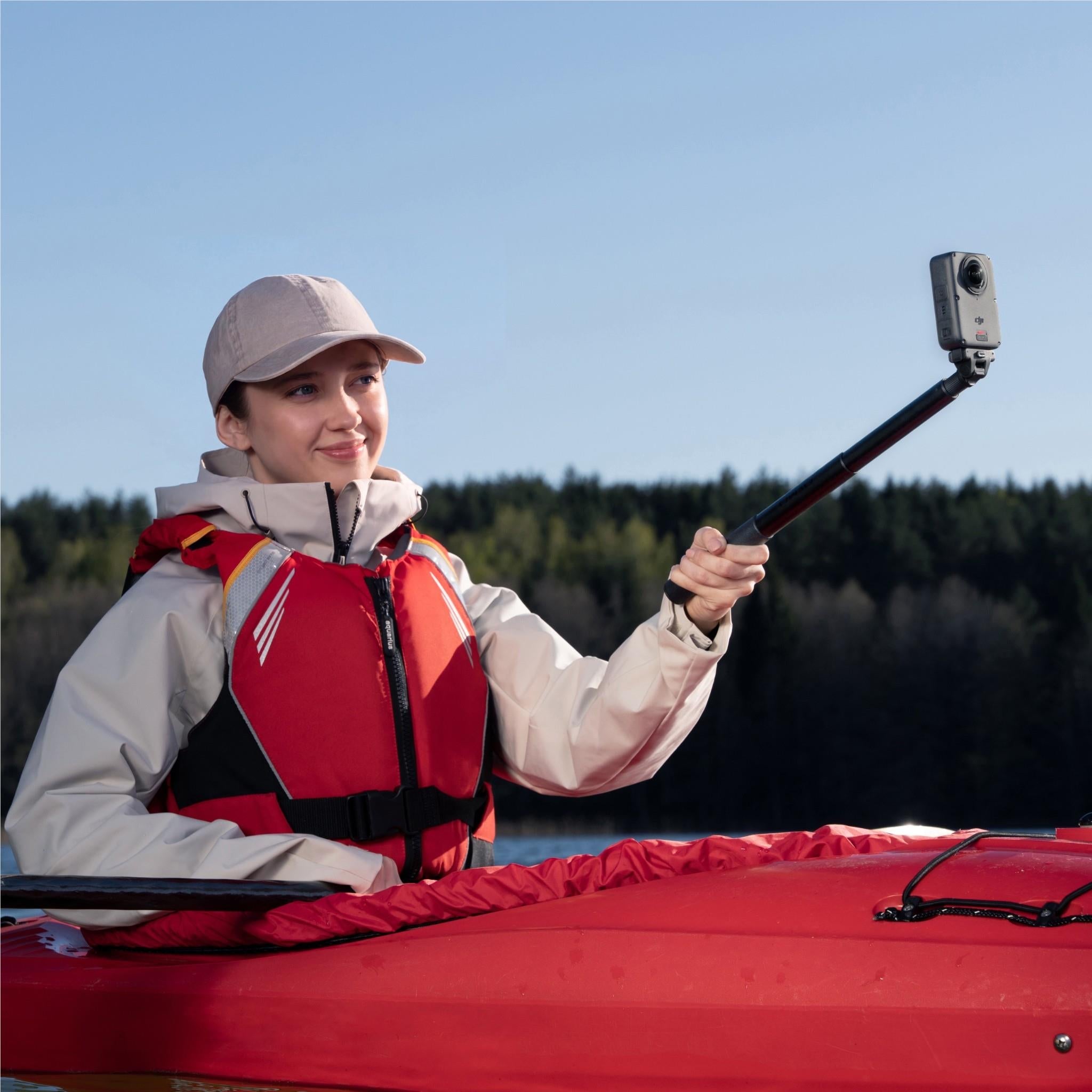 Action camera on a selfie stick held by an outdoor hiker in a life vest