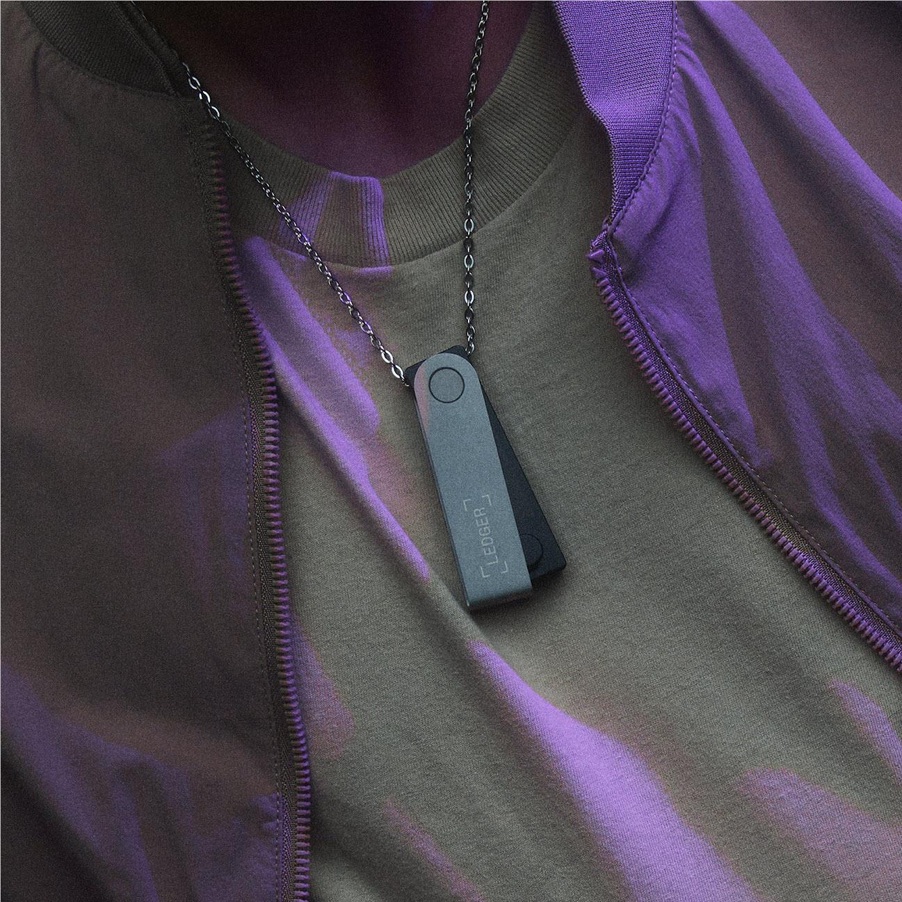 Green Ledger hardware wallet on a chain necklace attached to a zippered jacket