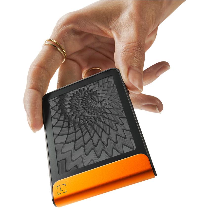 Ledger Flex wallet with textured black face and orange base, held in hand