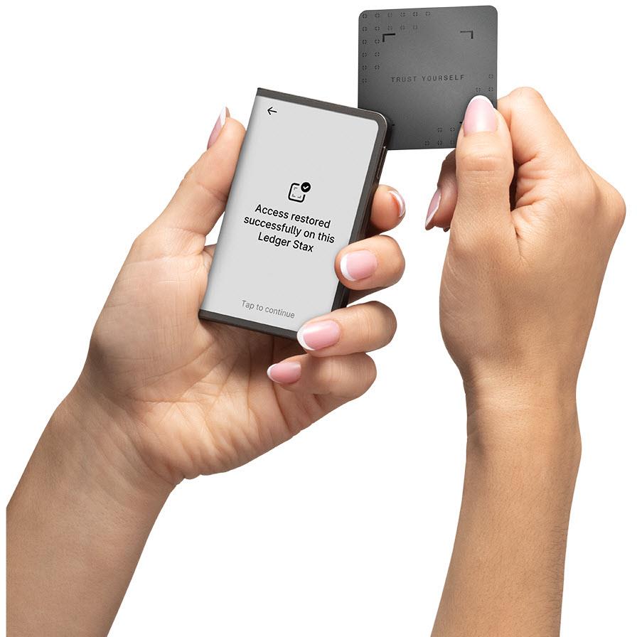 Graphite hardware wallet showing access message in hands with a second device