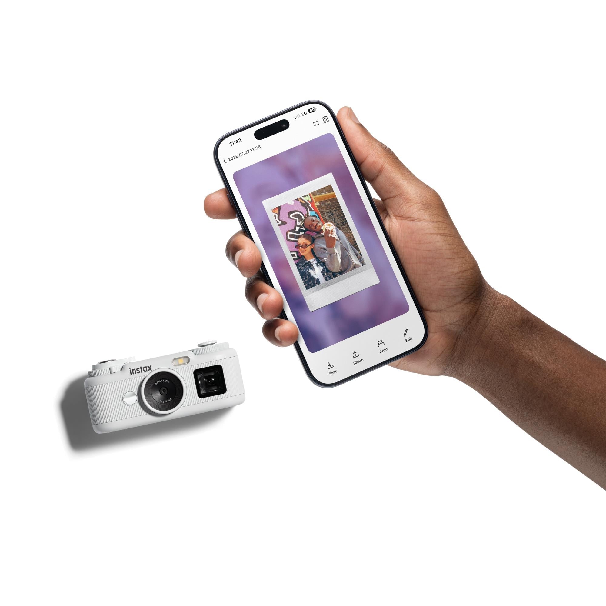 White instax pocket instant camera in hand with smartphone showing photo transfer