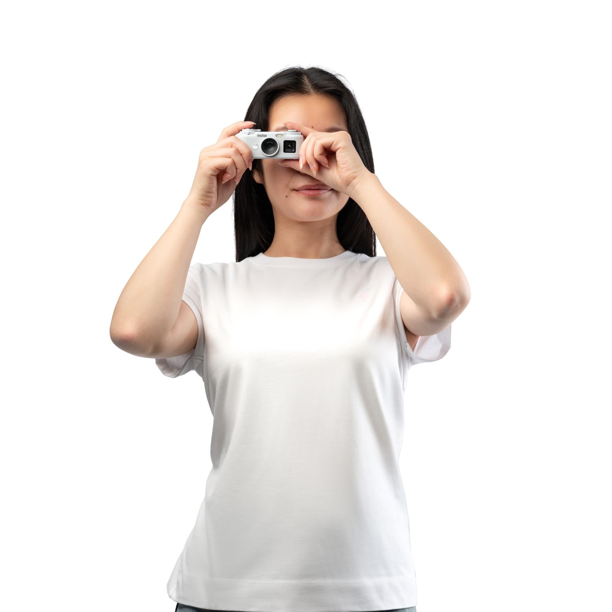 White instax pocket instant camera held up by person, ready to take a photo