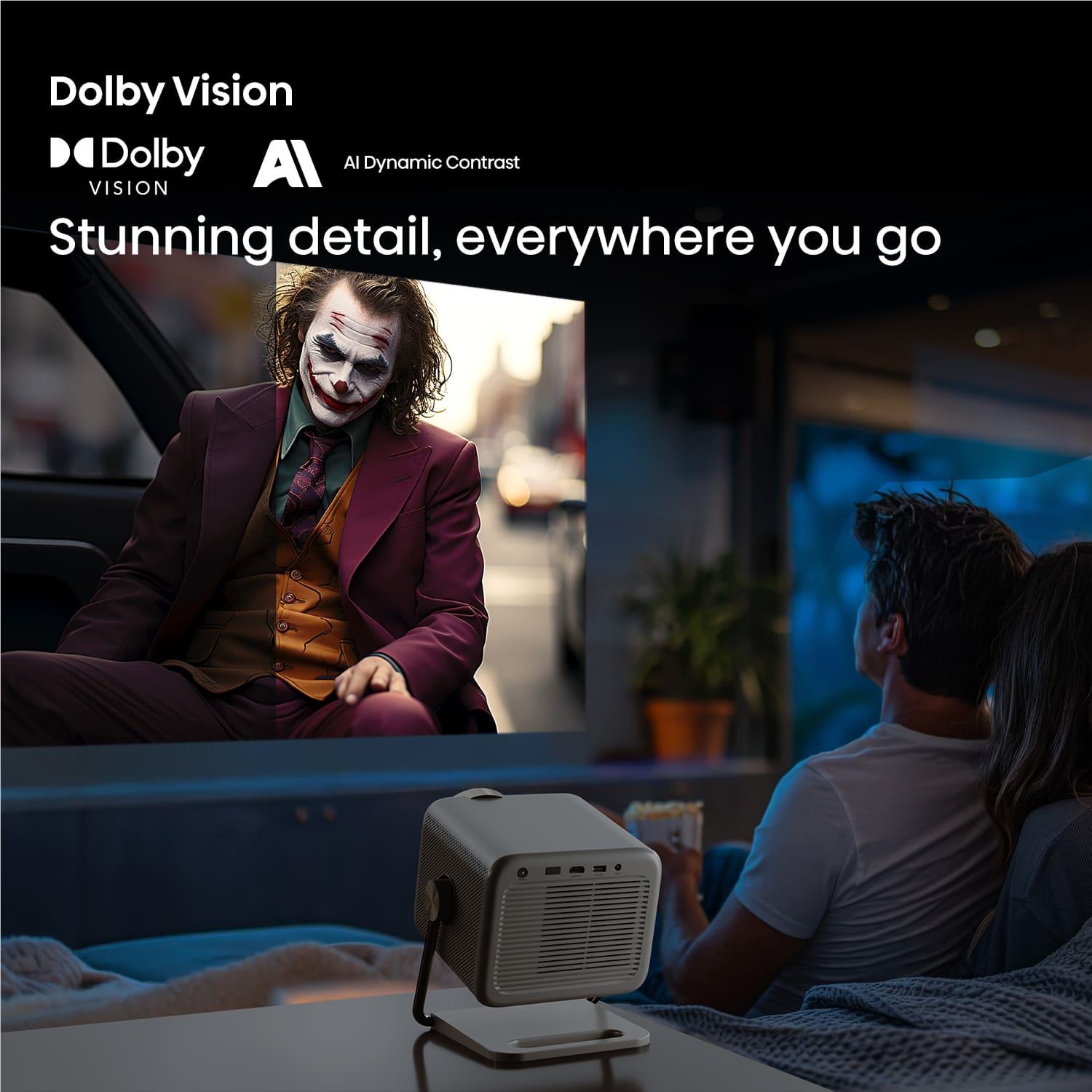 Small mini projector on a stand projecting a movie onto a screen in a dark room