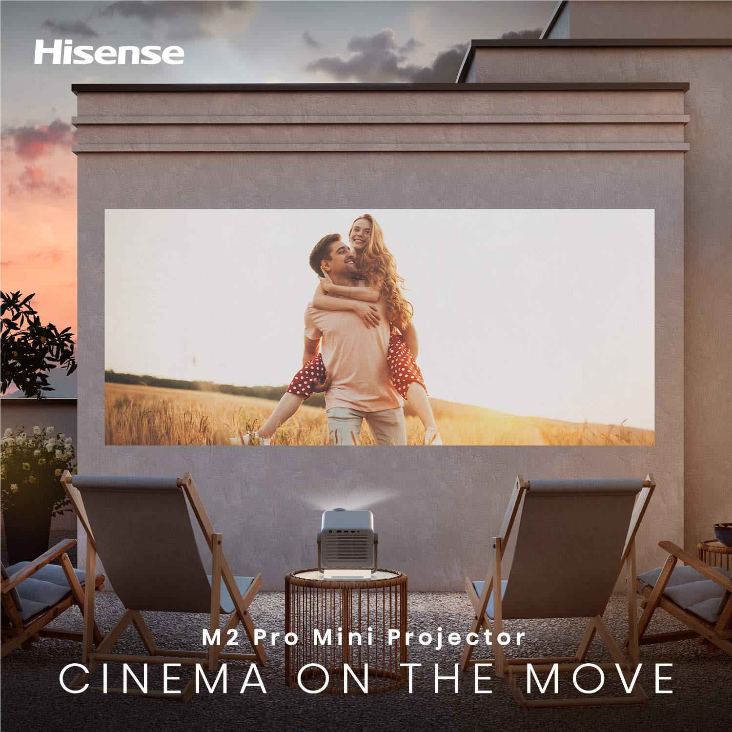 Mini projector on the ground in front of a large outdoor projection screen