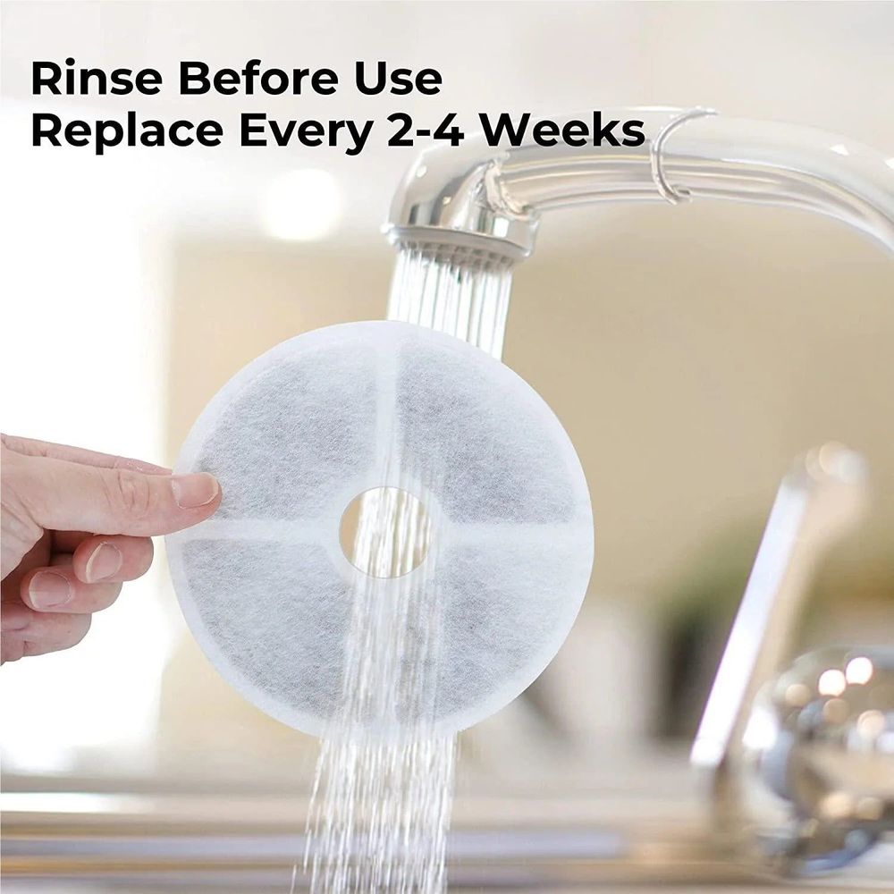 Round pet water fountain filter pad being rinsed under running water
