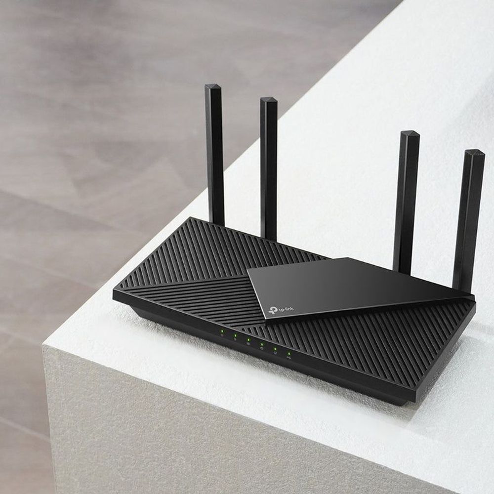 Black dual-band Wi‑Fi 6 router with four antennas and LED indicators on a stand