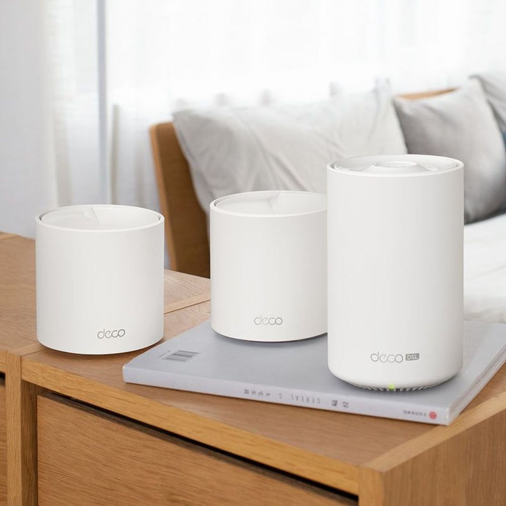Three white Deco mesh router units on a wooden bedside table