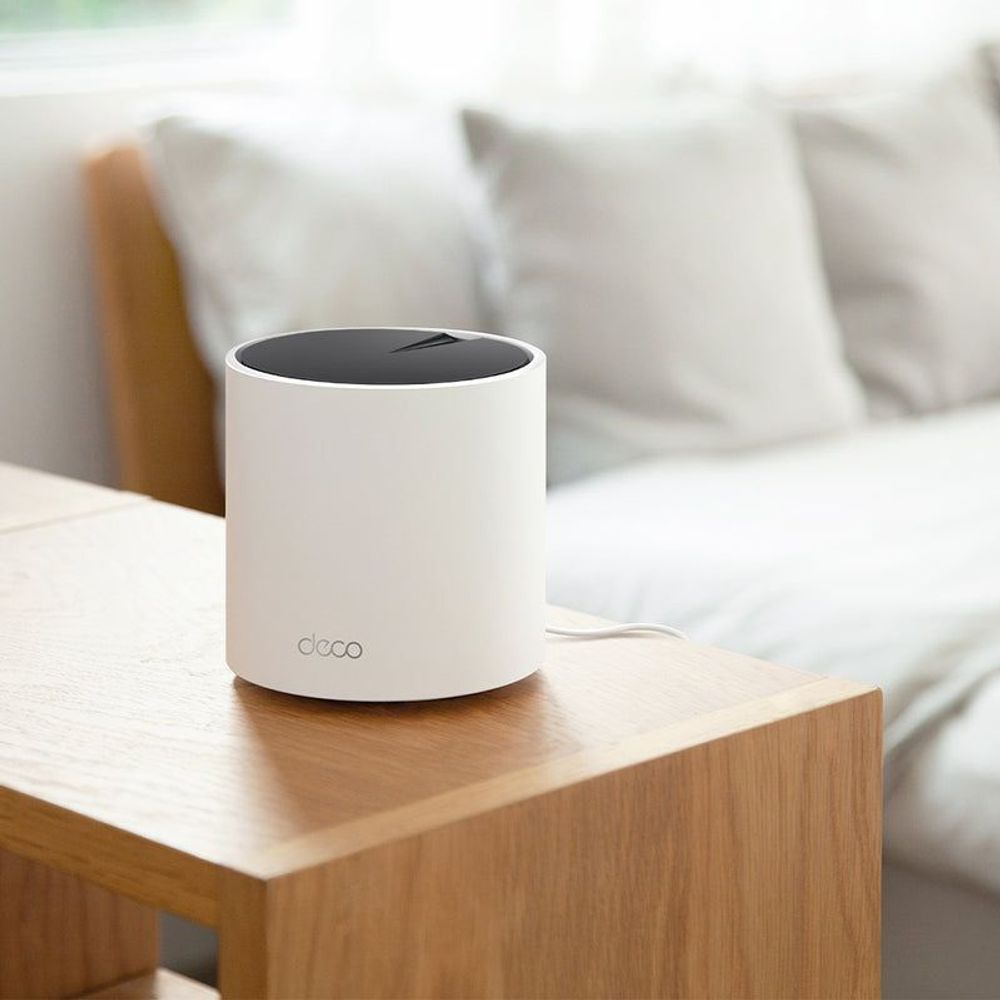 White Deco mesh WiFi 6 router on a wooden table with a black top
