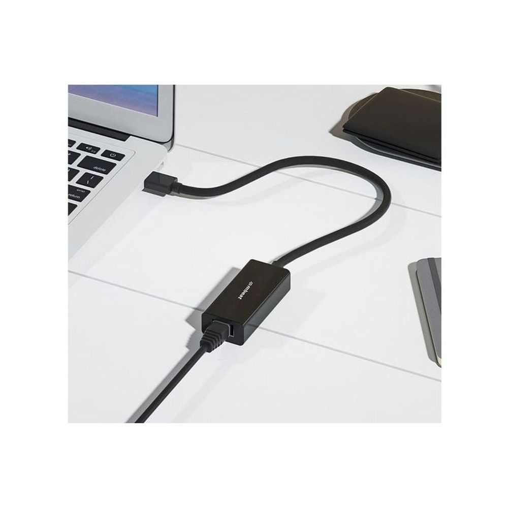 Black USB 3.0 gigabit Ethernet adapter connected to laptop with RJ45 cable