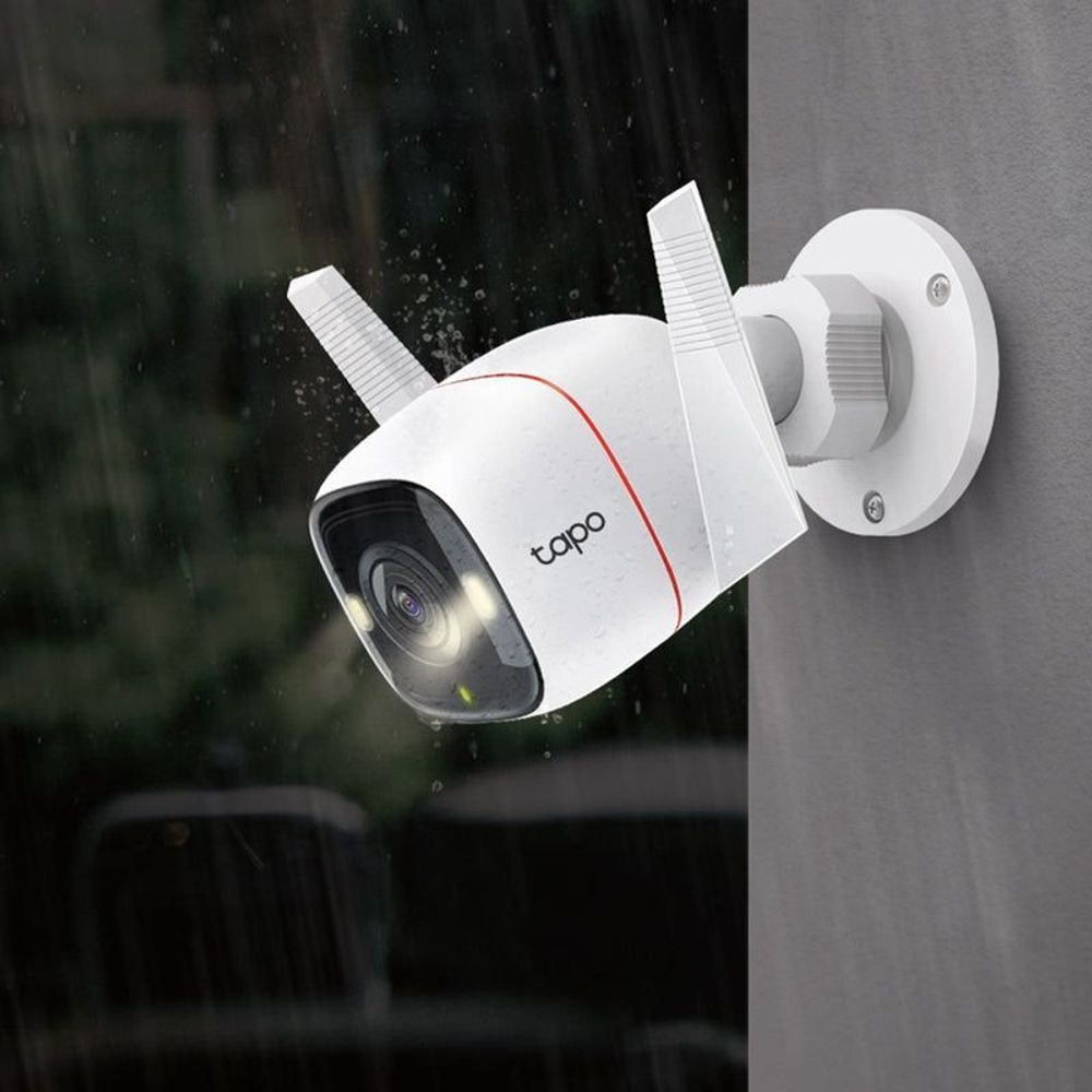 White tapo outdoor security camera mounted on wall with water droplets