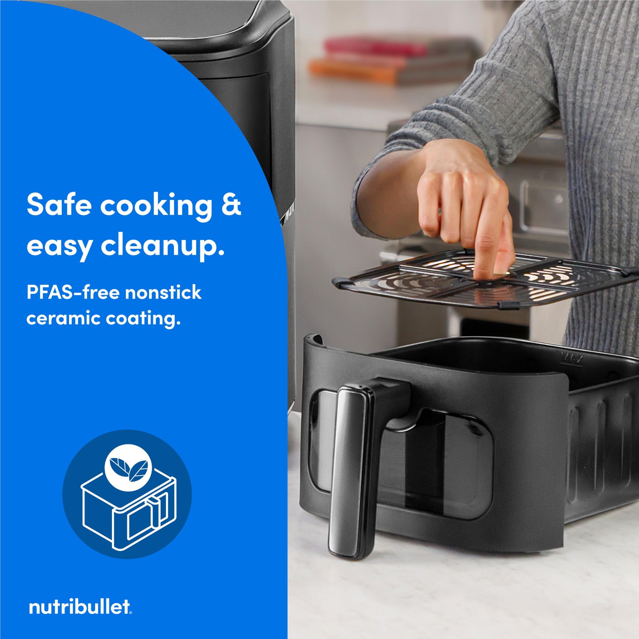 Black dual-basket air fryer with top drawer removed and wire rack held in hand