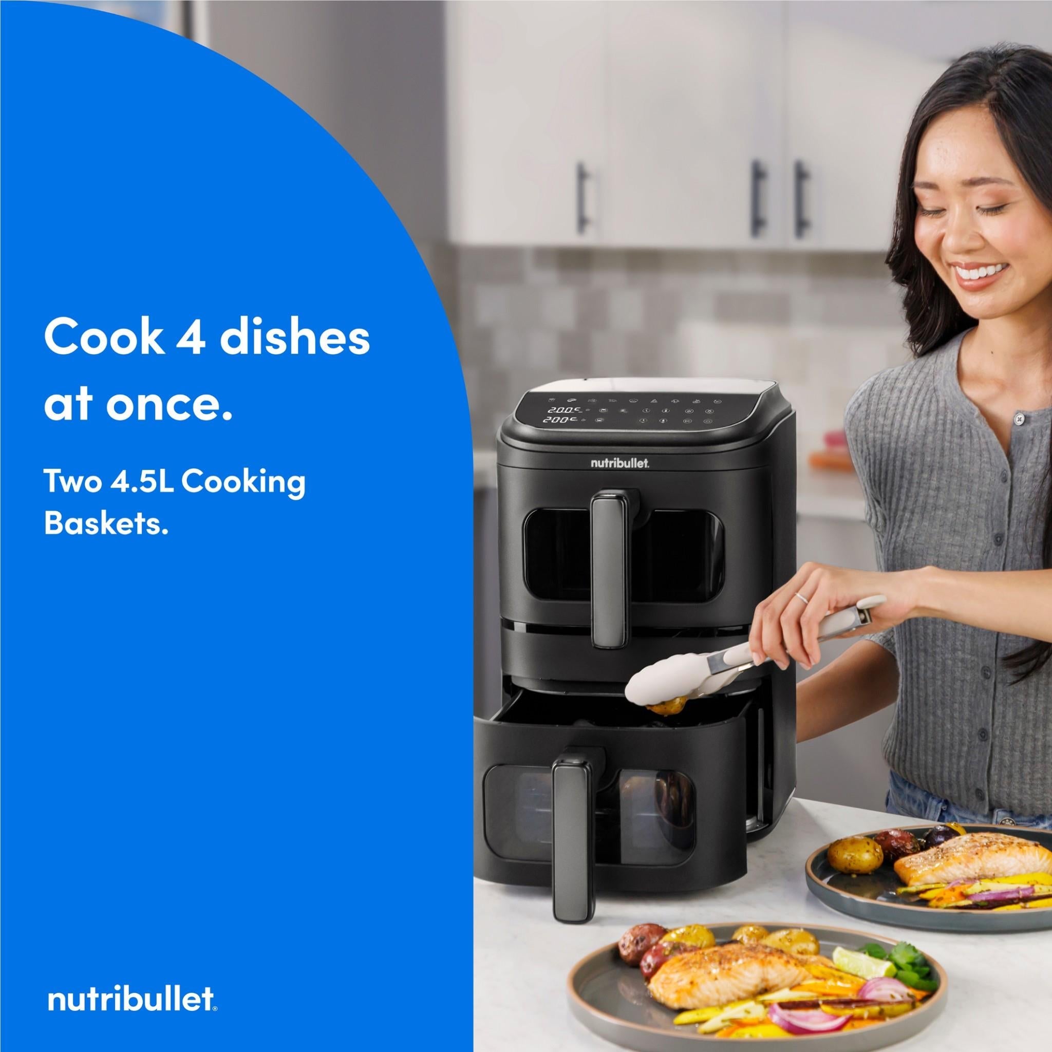 Black dual-basket air fryer on counter with woman holding utensil for cooking